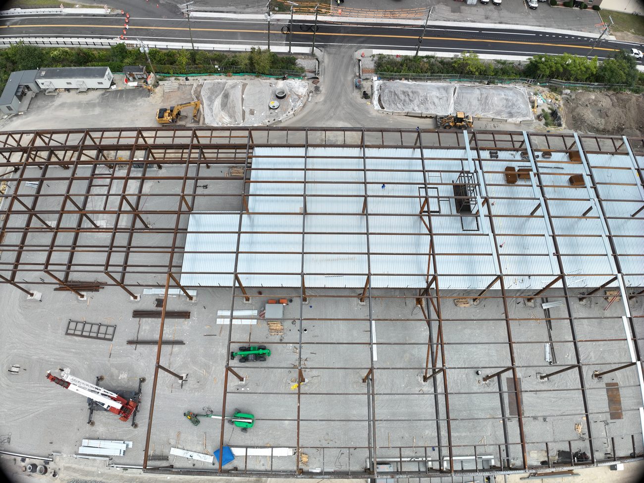 Straight-down aerial of a steel-framed building under construction, roof decking partly laid