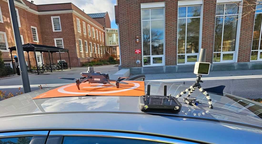 An enterprise quadcopter and its controller staged on an orange landing pad on a vehicle roof