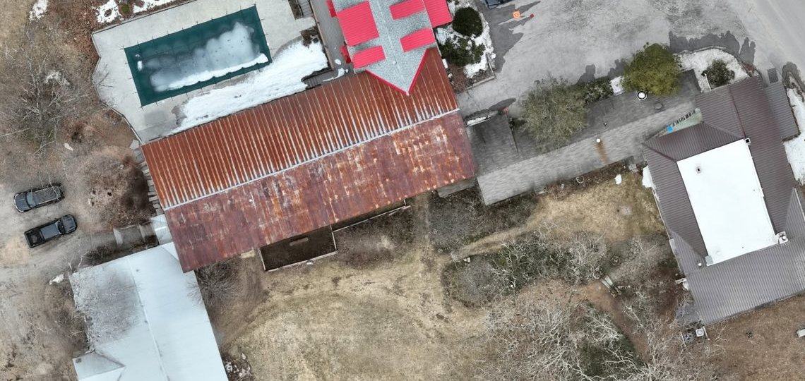 Straight-down aerial of farm buildings with sections of one metal roof marked in red