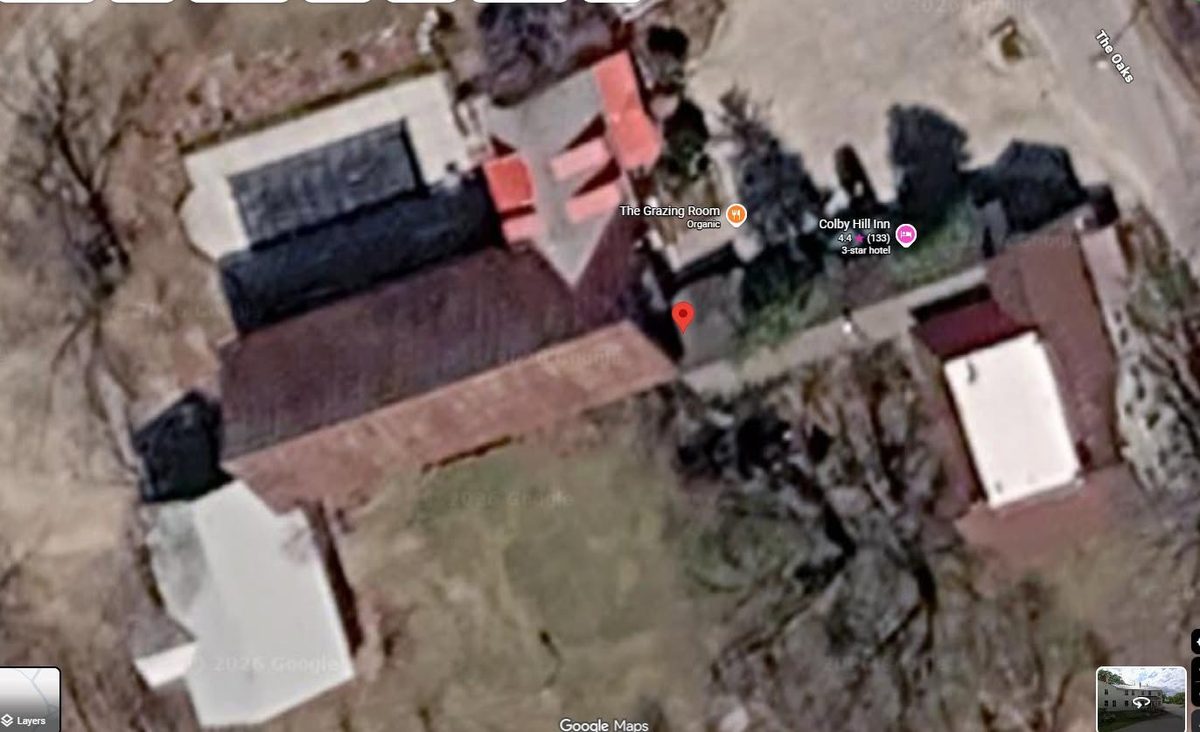 Low-resolution public satellite view of an inn and its outbuildings, roof detail indistinct